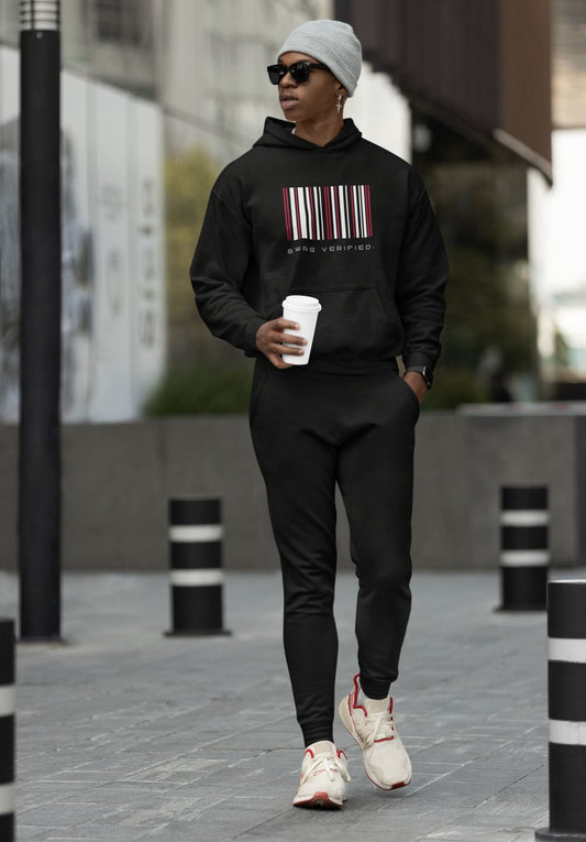 Confident man wearing black Swag Verified hoodie with black joggers while holding a coffee cup and walking in the city | Ohhh So Swag