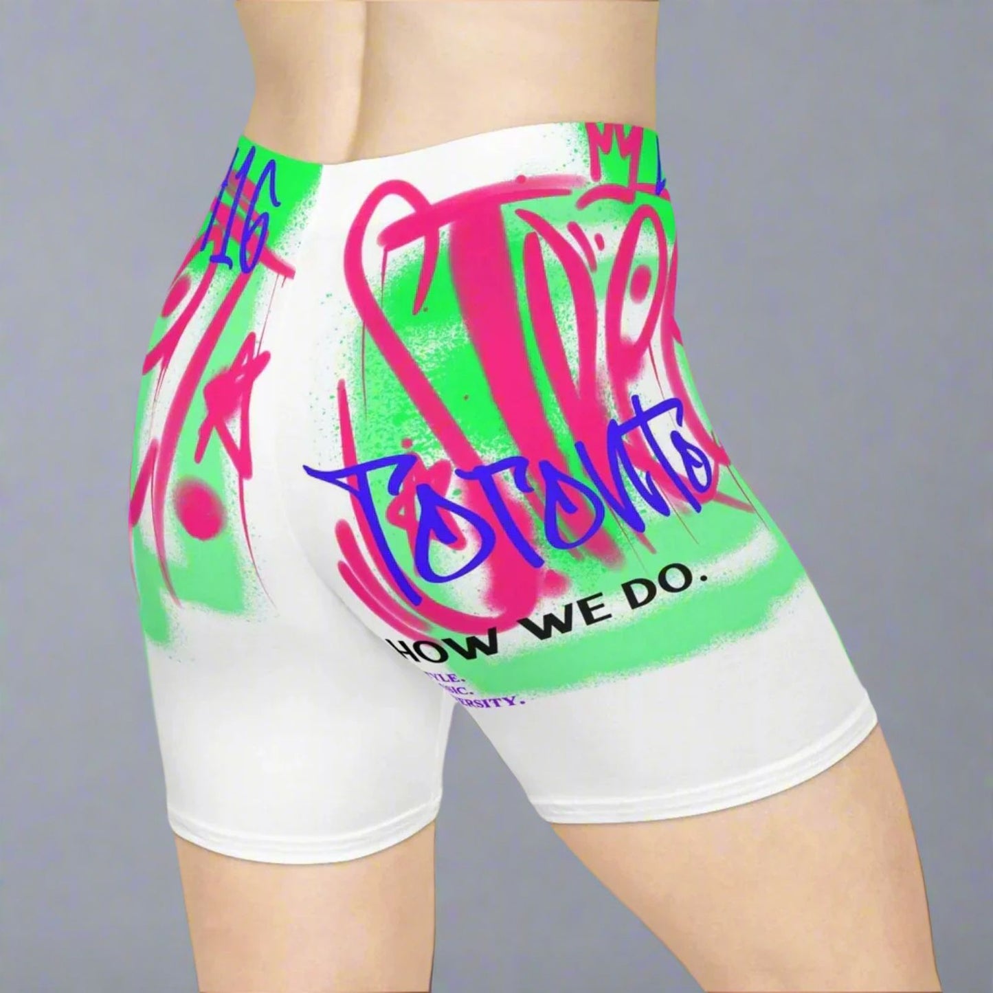 90s white Toronto shorts with colorful graphics and text by a gray background | Ohhh So Swag