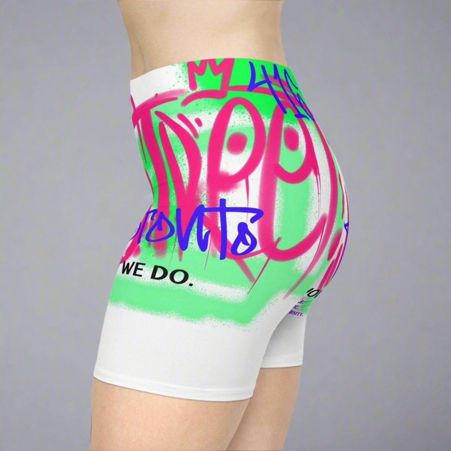 White biker shorts about Toronto with bright neon graffiti graphics worn in front of a gray background | Ohhh So Swag